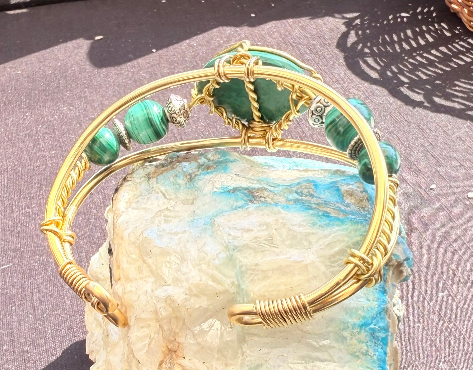 Gold bracelet with green gemstone on a textured surface malachite brass wire wrapped bracelet