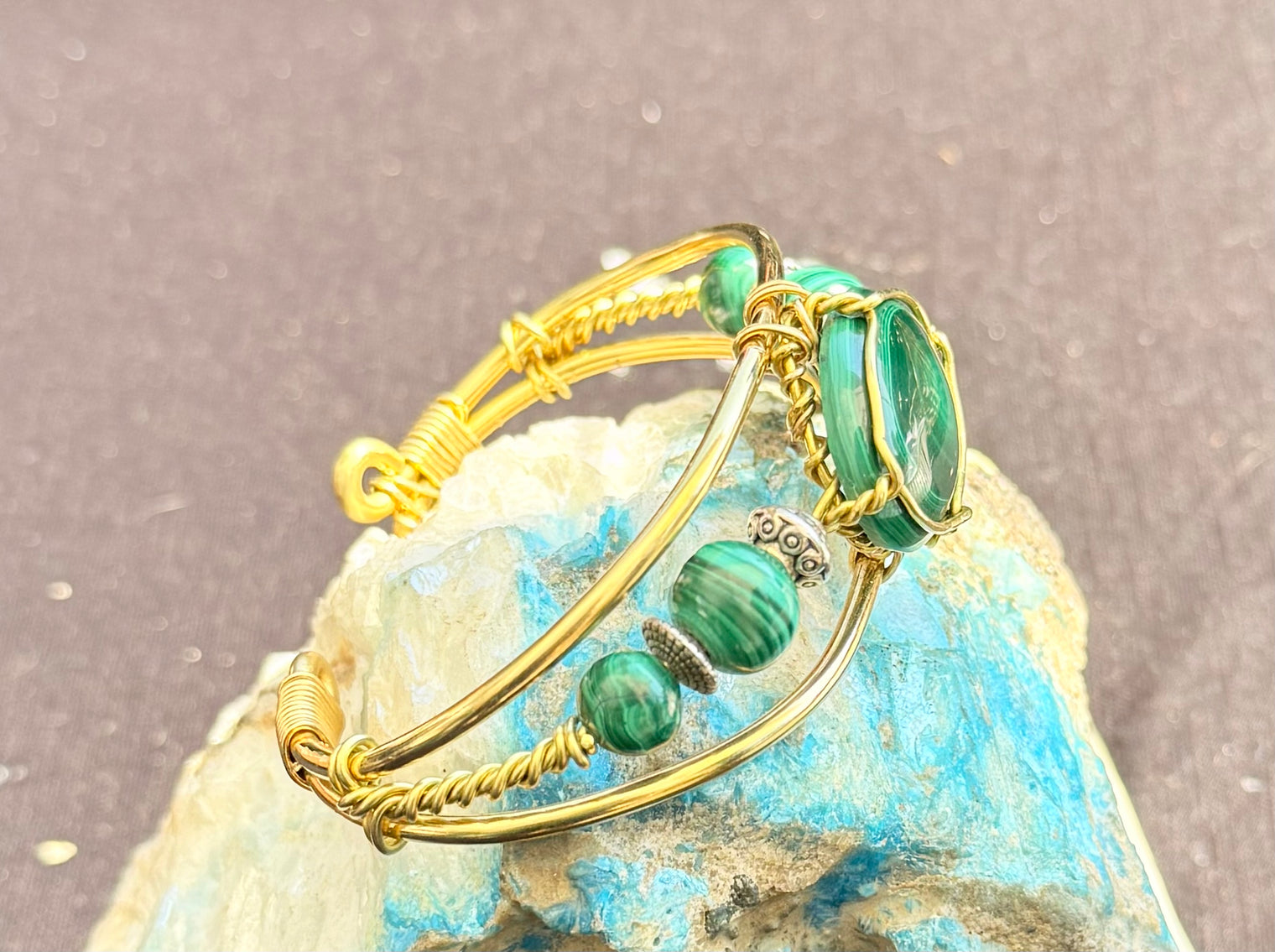 Gold bracelet with green gemstone on a textured surface malachite brass wire wrapped bracelet