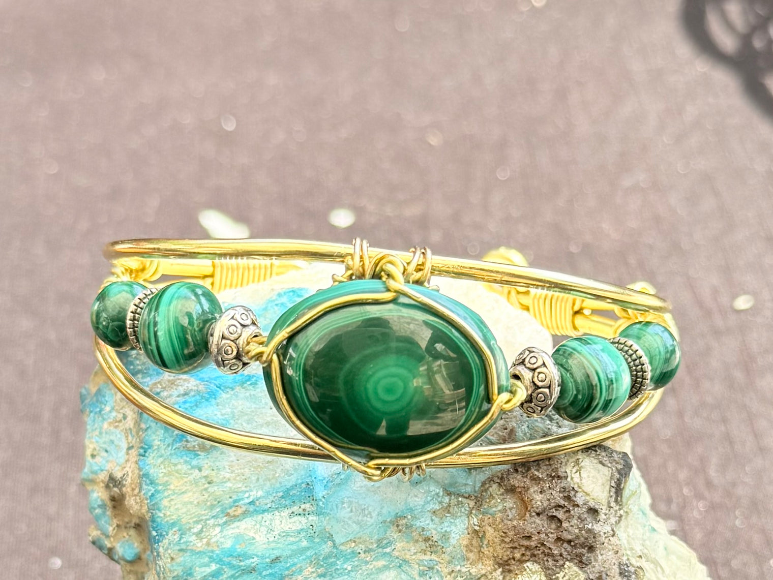 Gold bracelet with green gemstone on a textured surface malachite brass wire wrapped bracelet