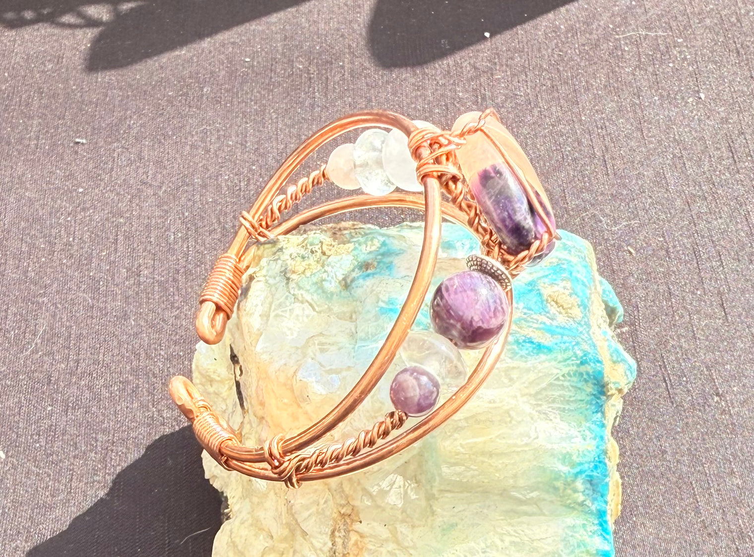 copper bracelet with rose quartz, clear quart and amethyst bonded cabochon and rose quartz and amethyst beads along the side of the wire wrapped bracelet