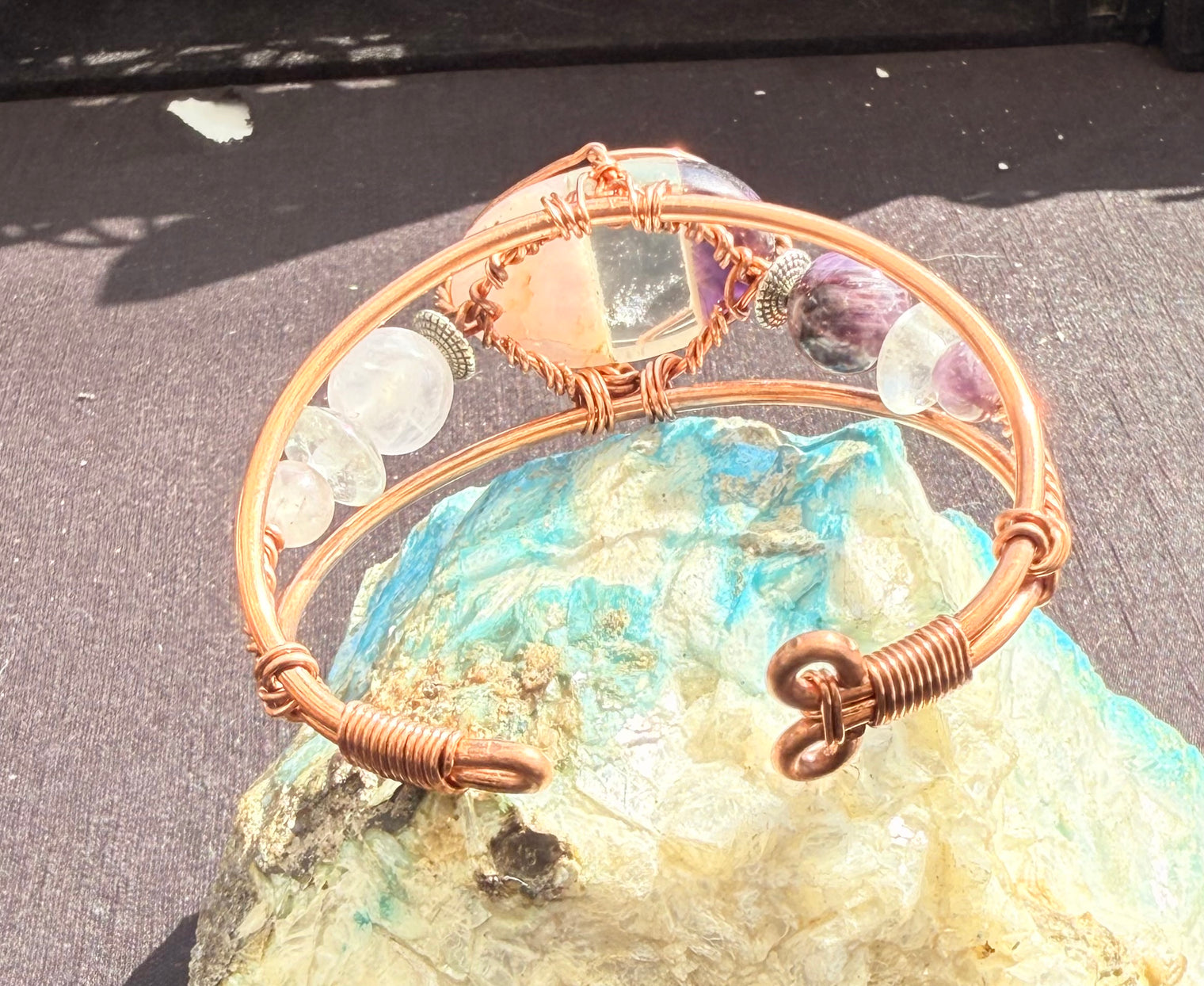 copper bracelet with rose quartz, clear quart and amethyst bonded cabochon and rose quartz and amethyst beads along the side of the wire wrapped bracelet