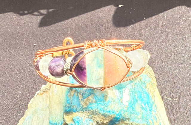 copper bracelet with rose quartz, clear quart and amethyst bonded cabochon and rose quartz and amethyst beads along the side of the wire wrapped bracelet