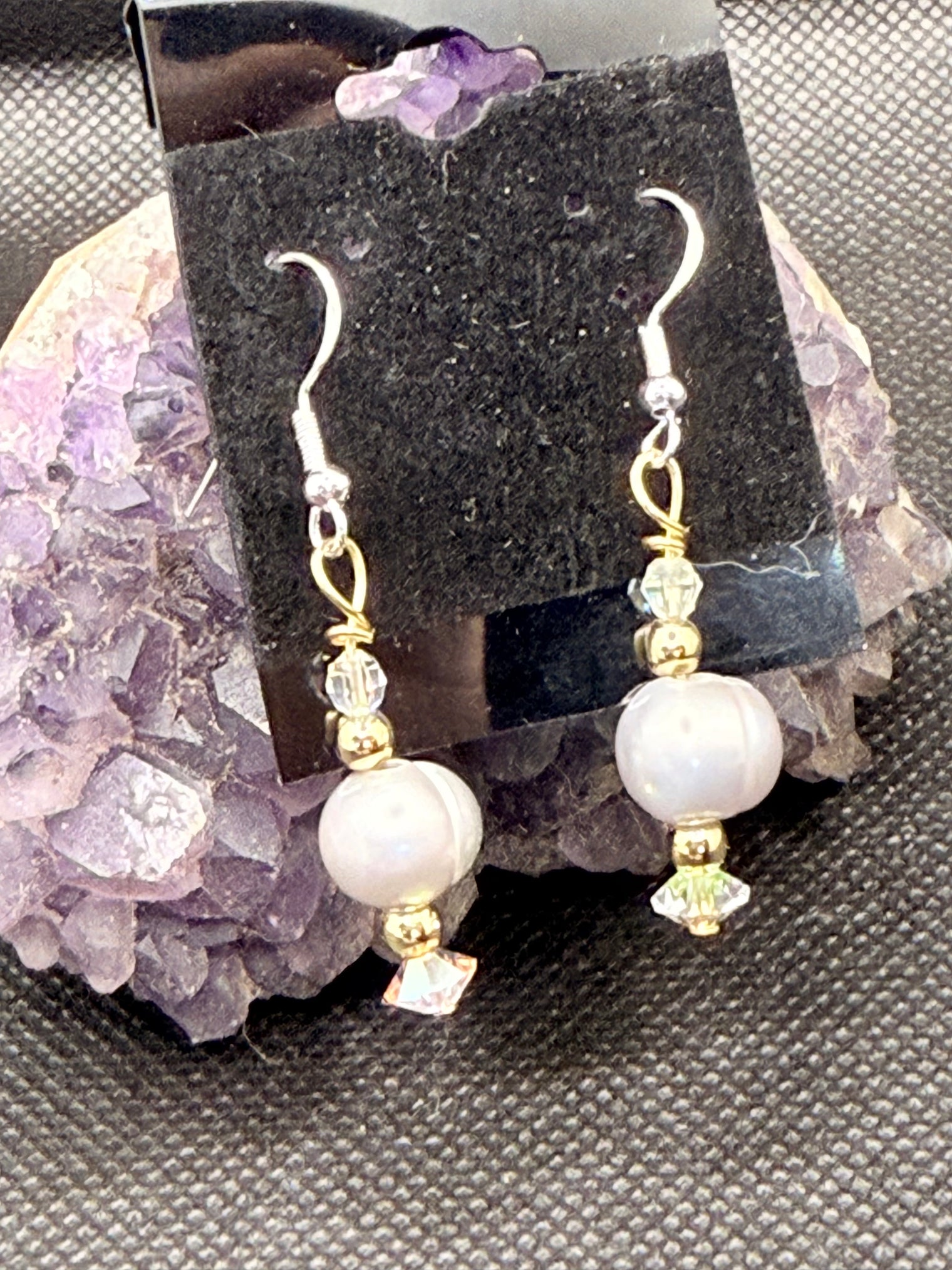 Pair of silver pearl and gold beaded earrings with Swarovski Crystals on a black card with a dark background