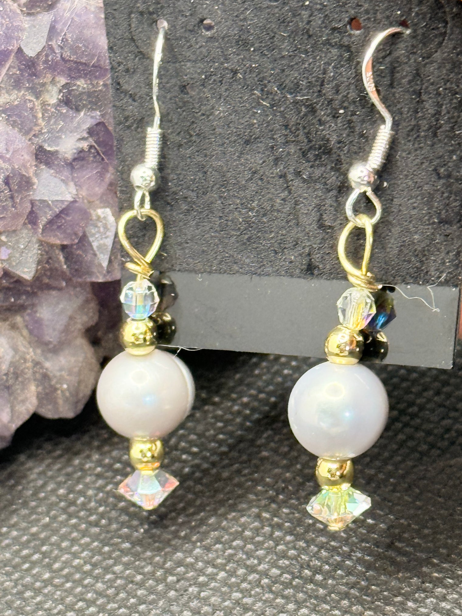 Pair of silver pearl and gold beaded earrings with Swarovski Crystals on a black card with a dark background