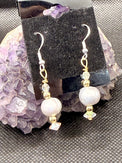 Pair of silver pearl and gold beaded earrings with Swarovski Crystals on a black card with a dark background